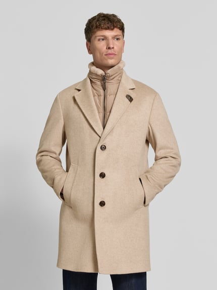 Männermodel trägt Regular Fit Mantel aus Woll-Mix Modell 'Morris' von JOOP! COLLECTION in Beige mit dunklen Knöpfen, Nahaufnahme Oberkörper.