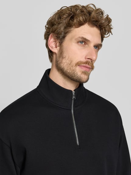 Männermodel trägt schwarzen Regular Fit Troyer aus Baumwoll-Mix Modell 'Dalizip' von HUGO, Herren Troyer, Nahaufnahme Oberkörper.