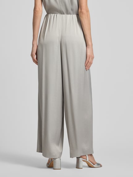 Frauenmodel trägt Loose Fit Stoffhose mit Stretch-Anteil von Drykorn aus Acetat-Elasthan-Mix, Damen, weite Beine, elastischer Bund, Ganzkörperansicht Rückansicht.