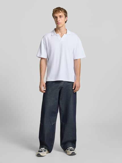 Männermodel trägt Boxy Fit Poloshirt aus Baumwoll-Mix Modell 'CASPIAN AIRLEX' von Only & Sons, weiß, kurzarm, unifarben, Polokragen, Label Patch, Jersey-Material, Ganzkörperansicht von vorne.