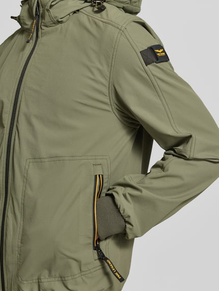 Männermodel trägt Jacke mit Kapuze und Reißverschlusstaschen von PME Legend in khaki, materiaalmix met stretch, regular fit, detailaufnahme Oberkörper. Ruglengte maat M: 71 cm, schouderbreedte: 46 cm, borstwijdte: 55 cm, mouwlengte: 66 cm.