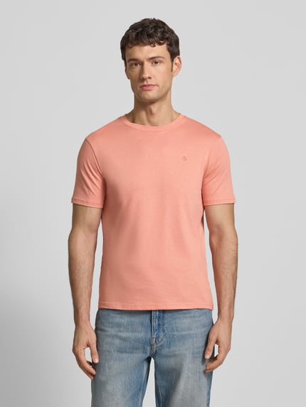 Männermodel trägt Regular Fit T-Shirt mit Logo-Stitching von Scotch & Soda in Rosa aus reiner Baumwolle, Rundhalsausschnitt, Ganzkörperansicht von vorne.