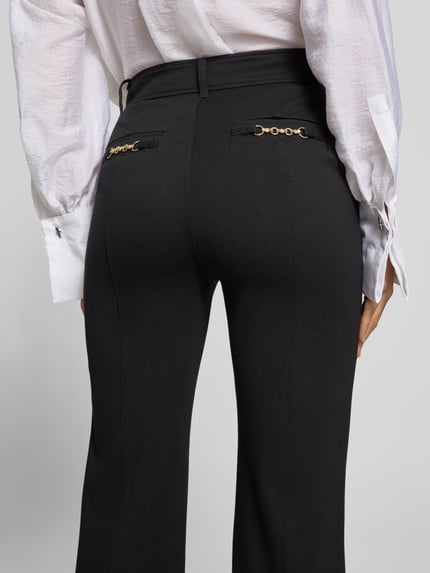 Frauenmodel trägt Flared Fit Anzughose aus elastischem Viskose-Mix Modell 'CHRISSY' von GUESS in Schwarz, Detailaufnahme Rückansicht, Damen Anzughose mit Gürtelschlaufen und seitlichen Eingrifftaschen, GUESS