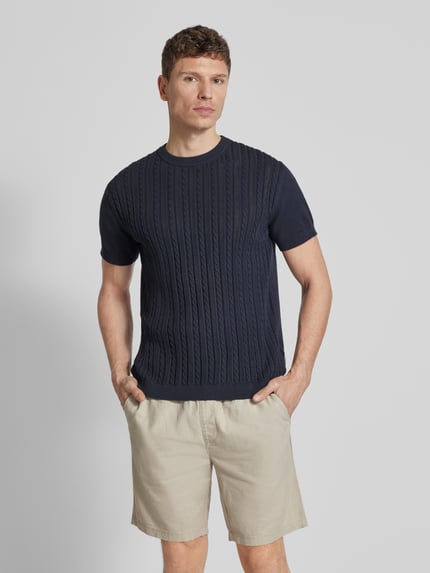 Männermodel trägt T-Shirt mit Zopfmuster von Lindbergh in Dunkelblau, reine Baumwolle, gerader Schnitt, Strick-Optik, Rundhalsausschnitt, Ganzkörperansicht von vorne.
