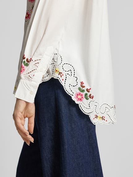 Frauenmodel trägt Modell 'JAYME' von Essentiel Antwerp, weiße Damen Langarmbluse mit floraler Stickerei, Nahaufnahme Oberkörper.