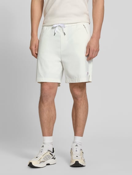 Männermodel trägt Relaxed Fit Sport-Shorts mit seitlichen Reißverschlusstaschen Modell 'Fisher' von BOSS Orange, Optik: Unifarben, Passform: Relaxed-Fit, Tunnelzug, Bundabschluss: Elastisch, Taschen: seitliche Reißverschlusstasche, helle Farbgebung, glatte Textur, Ganzkörperansicht von vorne.