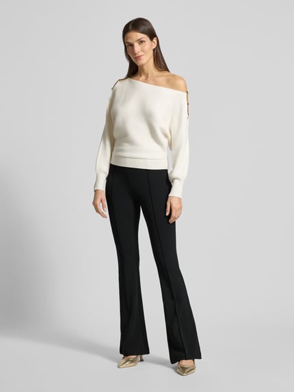 Frauenmodel trägt Flared Fit Stoffhose mit elastischem Bund Modell 'Evelina' von Guess, Schwarz, Ziernähte, Ganzkörperansicht von vorne.