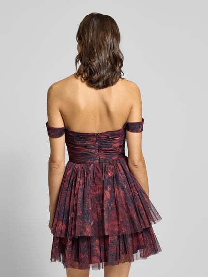 Modelka kobieca nosi Cocktailkleid aus Mesh im Off-Shoulder-Look od Jake*s Cocktail, bordowe i czarne warstwy, fason mini, ujęcie całej sylwetki od tyłu.