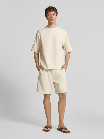 Männermodel trägt Shorts in Plissee-Optik mit elastischem Bund von REVIEW, Material-Mix mit Stretch-Anteil, Regular-Fit, Ganzkörperansicht von vorne.