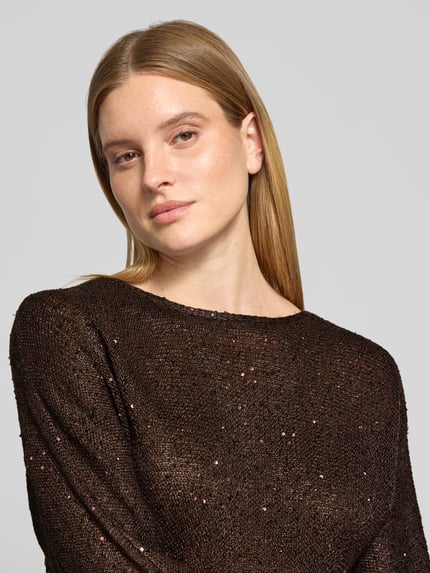 Frauenmodel trägt Pullover mit Strickstruktur und feinen Glanzeffekten von VERO MODA, dunkle Farbe, Nahaufnahme Oberkörper.