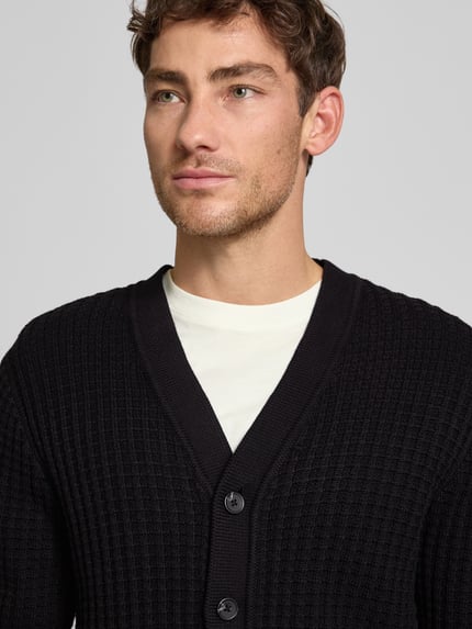 Männermodel trägt Herren Strickjacke aus reiner Baumwolle Modell 'TOM' von SELECTED HOMME, unifarben, Waffelstruktur, Nahaufnahme Oberkörper.