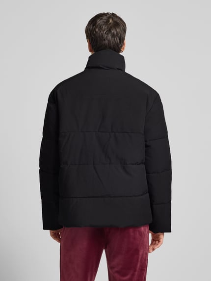 Männermodel trägt schwarze Steppjacke mit Stehkragen Modell 'NILO' von SERGIO TACCHINI, Material-Mix und Stretch-Anteil, Ganzkörperansicht Rückansicht.
