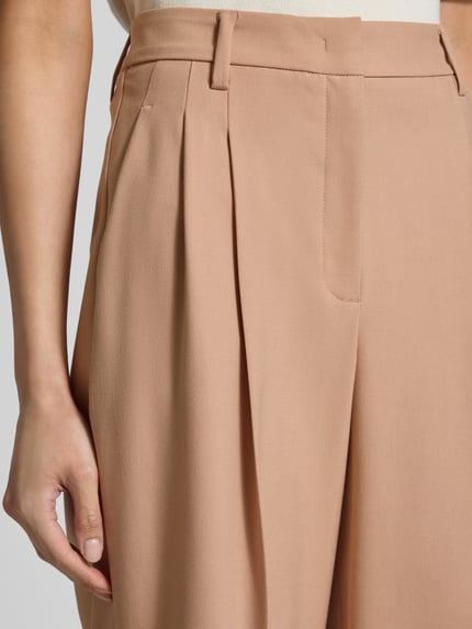 Frauenmodel trägt Straight Fit Hose mit Viskose-Anteil in verkürzter Passform von Luisa Cerano, beige, Bundfalten, Nahaufnahme Oberkörper. Elastischer Material-Mix, Haken- und Reißverschluss, glatte Textur.