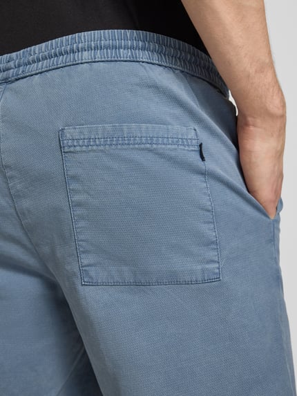 Männermodel trägt Shorts mit elastischem Bund Modell 'JAIDEN CARTER' von Jack & Jones aus Baumwoll-Elasthan-Mix in Blau, Strukturmuster, Nahaufnahme Rückansicht, Regular-Fit, Kontext: Herren Shorts, Bundweite Größe M 43 cm, Innenbeinlänge 20 cm.
