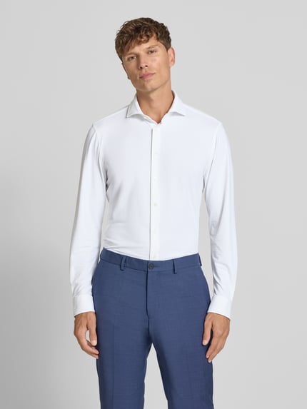 Männermodel trägt Slim Fit Business-Hemd mit Haifischkragen von Jake*s, weiß, feines Strukturmuster, Material-Mix mit Stretch-Anteil, Ganzkörperansicht von vorne. Rückenlänge 78 cm, Schulterbreite 48 cm, Ärmellänge 68 cm bei Größe 39/40.