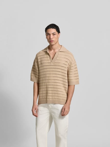 Männermodel trägt Relaxed Fit Poloshirt mit Viskose-Anteil von MAISON KITSUNÉ in Strick-Optik und Lochmuster, beige, ganzkörperansicht von vorne.