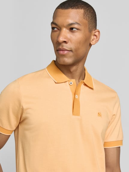 Männermodel trägt Regular Fit Poloshirt mit Logo-Stitching von Lerros in Hellorange, Polokragen, kurze Knopfleiste, Nahaufnahme Oberkörper.