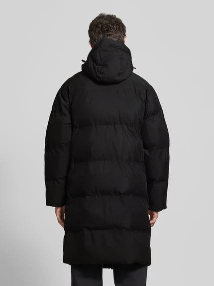 Männermodel trägt zwarte Regular Fit Steppmantel met steekzakken, Capuchon, ritssluiting, Ruglengte maat M 110 cm, Regular Fit Steppmantel mit Eingrifftaschen van Lindbergh, Ganzkörperansicht Rückansicht.