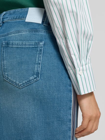 Vrouwenmodel draagt Regular Fit midirok in denimlook met loopsplit, 5-pocketmodel van Marc Cain, mix van katoen en elastaan, detailopname rug.