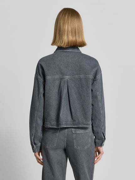 Frauenmodel trägt Boxy Fit Jeansjacke mit aufgesetzten Taschen Modell 'Niandra' von Someday aus reiner Baumwolle, Rückansicht, Ganzkörperansicht.