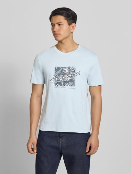 Mężczyzna nosi męski t-shirt z nadrukiem, okrągły dekolt, bawełna, krój regular fit, T-Shirt mit Rundhalsausschnitt Modell 'HONOLULU' od Jack & Jones, długość tyłu w rozmiarze M: 68 cm, jasnoniebieski, gładka tekstura, widok całego ciała z przodu