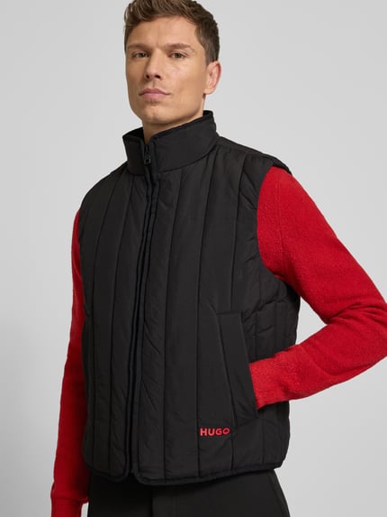 Männermodel draagt Regular Fit Steppweste uit waterafstotend materiaal model 'BRENO2611' van HUGO, zwart, met opstaande kraag en zijzakken, labelprint, unikleurig, Ganzkörperansicht von vorne.