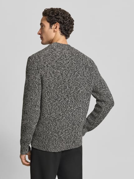 Männermodel trägt Pullover Modell 'Suolaa' mit Rippabschlüssen von HUGO in Melange-Strickoptik, Strukturmuster, Ganzkörperansicht Rückansicht.