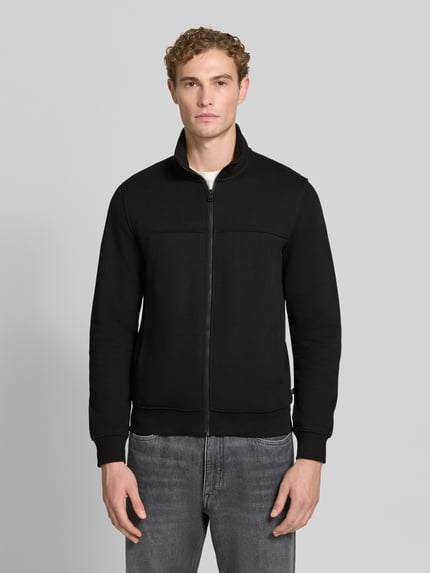 Männermodel trägt schwarze Regular Fit Sweatjacke aus Baumwoll-Mix von s.Oliver RED LABEL, dezente Textur, Ganzkörperansicht von vorne.