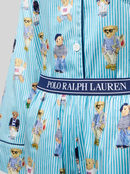 Mädchen trägt Comfort Fit Pyjama aus reiner Baumwolle Modell 'Iconic Bear' von Polo Ralph Lauren, niebieski w paski, nadruk z motywem misia, detal z logo na elastycznym pasku, popelina, detaliczne ujęcie przodu.