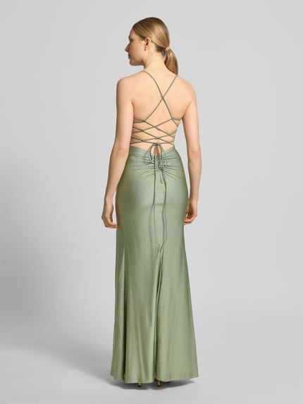 Frauenmodel trägt Maxikleid mit Drapierungen und Gehschlitz von Mascara aus schimmerndem, grünem Satin, figurbetont, Ganzkörperansicht Rückansicht.