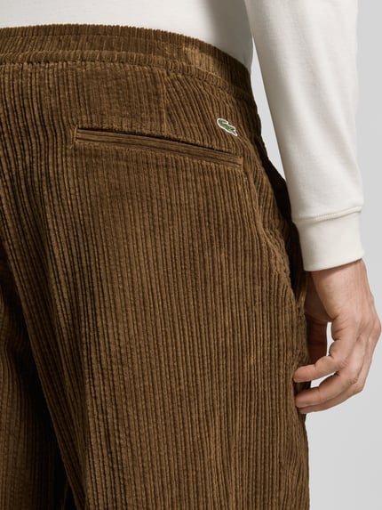 Männermodel trägt Regular Fit Hose mit seitlichen Eingrifftaschen von Lacoste, brauner Cord mit Struktur, Nahaufnahme Hüfte