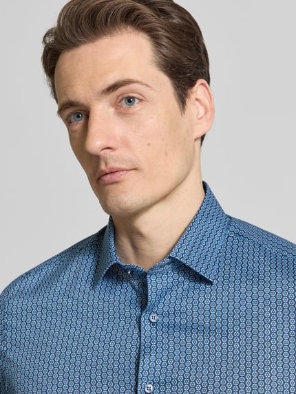 Männermodel trägt OLYMP Level Five Body Fit Business-Hemd mit extra langem arm, blauw met geometrisch patroon, Kentkraag, mix van katoen en elastaan, knoopsluiting, heren zakelijk hemd van OLYMP, Nahaufnahme Oberkörper. Ruglengte 82 cm, schouderbreedte 44 cm, mouwlengte 72 cm bij maat 40L.