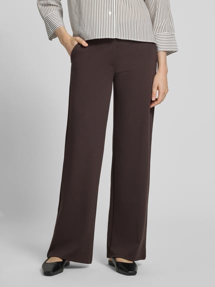 Frauenmodel trägt Straight Fit Stoffhose mit Viskose-Anteil Modell 'Nanni' von FREE/QUENT in Dunkelbraun, glatte Struktur, Nahaufnahme Unterkörper. Damen Stoffhose mit elastischem Material-Mix, Haken- und Reißverschluss, Bundweite 37 cm, Innenbeinlänge 77 cm.