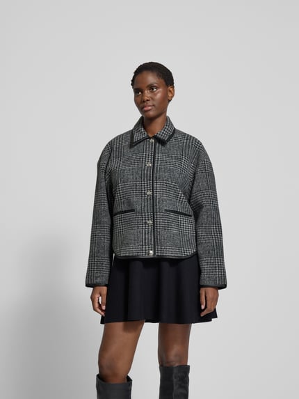 Frauenmodel trägt Jacke mit Knopfleiste von Anine Bing, mieszanka materiałów z dodatkiem wełny, luźny krój, kołnierzyk koszulowy, wpuszczane kieszenie, długość tyłu 60 cm, szerokość klatki piersiowej 57 cm, długość rękawów 53 cm; szaro-czarna kolorystyka i tekstura w kratę, całkowity widok z przodu