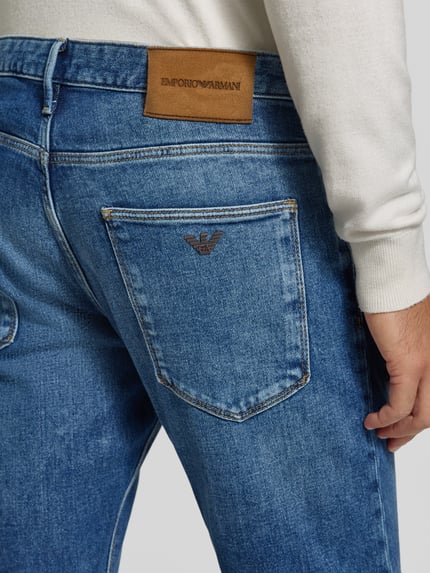 Männermodel trägt Slim Fit Jeans im 5-Pocket-Design von Emporio Armani, blaue Baumwoll-Mix Struktur, Detailaufnahme Rückansicht.