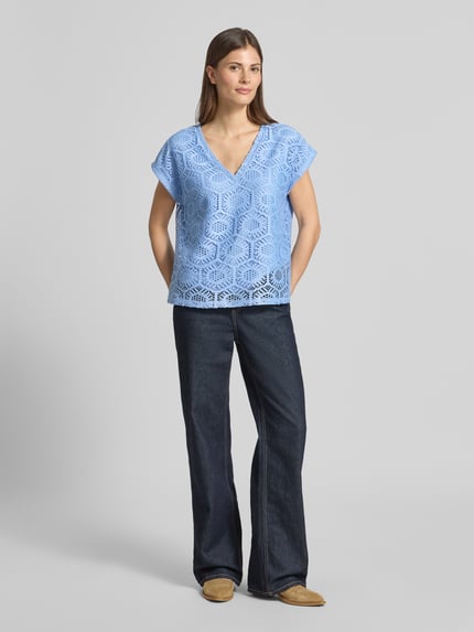 Kobiece modelka ma na sobie damski t-shirt Boxy Fit T-Shirt mit semitransparentem Besatz Modell 'IRIS' od Vero Moda, efekt: jednolity kolor, wzór: abstrakcyjny, półprzezroczyste obszycie, dekolt w serek, bez rękawów, wykończenie materiału: ażur, stretch. Ganzkörperansicht von vorne.
