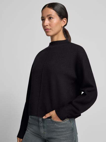 Frauenmodel trägt Strickpullunder Modell 'Punus' mit Mock Neck von OPUS, unifarben, hochgeschlossen, ärmellos, abgerundeter Rumpfabschluss, Nahaufnahme Oberkörper.