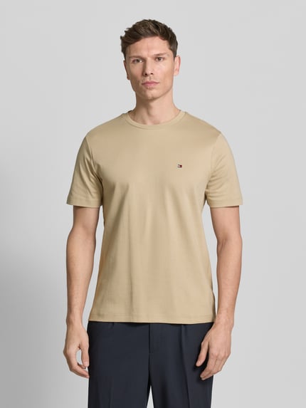 Männermodel trägt Regular Fit T-Shirt aus reiner Baumwolle von Tommy Hilfiger in uni beige, kurzarm, Rundhals, met logo-detail, ganzkörperansicht von vorne.