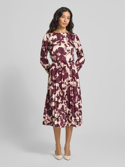 Frauenmodel trägt Cocktailkleid mit Rundhalsausschnitt von Rinascimento aus Material-Mix mit Stretch-Anteil, Plisseefalten, creme-bordeaux, körpernahe Passform, Ganzkörperansicht von vorne.