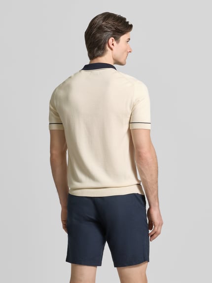 Männermodel trägt Slim Fit Poloshirt mit Logo-Stitching von Gant, Beige mit dunkelblauem Kragen, Baumwoll-Modal-Mix, Ganzkörperansicht Rückansicht.