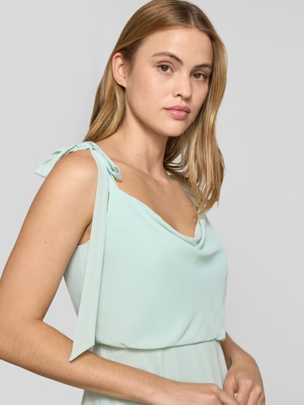 Frauenmodel trägt Knielanges Cocktailkleid mit Zierschleifen von Jake*s Cocktail in zartem Pastell, Ärmelloses-Design, tailliert, Nahaufnahme Oberkörper. Rückenlänge in Größe 36 beträgt 97 cm, Brustweite 33 cm, blickdichter Unterrock, angenehme Textur.