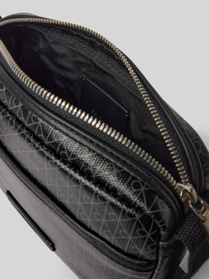 Produktfoto, Handtasche mit Logo-Muster und Schulterriemen von CK Calvin Klein, Hauptfach mit Reißverschluss, Label-Detail, schwarze Struktur, Maße: 22 cm Breite, 16 cm Länge, 5 cm Tiefe, Schulterriemen 106 cm, Herren Accessoire.