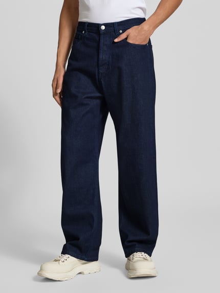 Männermodel trägt Wide Fit Jeans aus reiner Baumwolle von MAISON KITSUNÉ, dunkle gleichmäßige Waschung, 5-Pocket, Ganzkörperansicht von vorne. Innenbeinlänge 78 cm, Bundweite 45 cm, Knopf- und Reißverschluss.