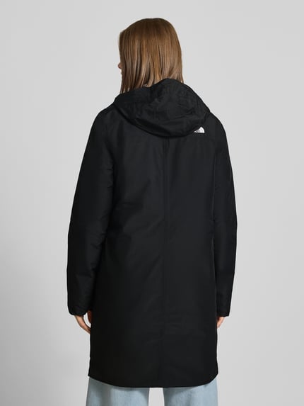 Vrouwenmodel draagt lange jas met capuchon Model 'SUZANNE' van The North Face, zwart, recht pasvorm, ruglengte maat S 92 cm, schouderbreedte 40 cm, borstwijdte 48 cm, mouwlengte 66 cm, steekzakken, labeldetail, rugaanzicht.