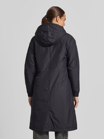 Frauenmodel trägt Regular Fit Mantel mit Logo-Print Modell 'DELIA' von K-WAY, dunkle Farbe, glatte Textur, Kapuze mit Tunnelzug, Ganzkörperansicht Rückansicht. Rückenlänge 101 cm, Schulterbreite 51 cm, Brustweite 52 cm, Ärmellänge 57 cm, 10.000 Wassersäule.