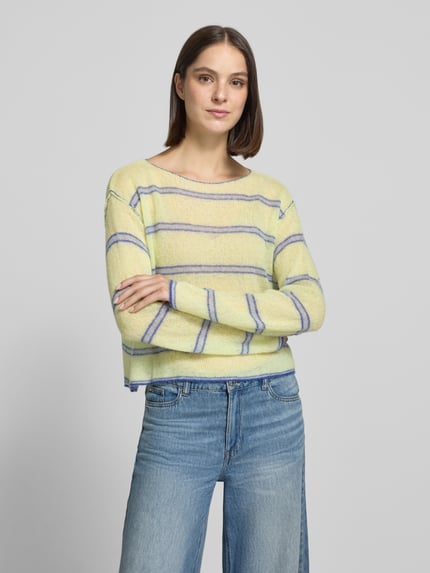 Frauenmodel trägt Relaxed Fit Strickpullover aus Lyocell-Mix Modell 'BODYROW' von American Vintage in Gelb mit blauen Streifen, Damen Strickpullover, U-Boot-Ausschnitt, langärmelig, überschnittene Schultern, Materialmix mit Lanawoll-Anteil, Ganzkörperansicht von vorne.