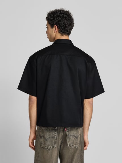 Männermodel trägt Relaxed Fit Freizeithemd mit Brusttasche von REVIEW in Schwarz, Material-Mix, 1/2-Arm, Rückenlänge 67 cm, Ganzkörperansicht Rückansicht.