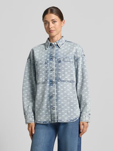 Kobiece model prezentuje Oversized Jeansbluse mit Alpaka-Anteil od Armani Exchange, elastyczna mieszanka materiałów, kołnierzyk koszulowy, listwa guzikowa na całej długości, nakładane kieszenie na piersi, szerokie ramiona, nadruk z logo na całej powierzchni, długość tyłu w rozmiarze S: 45 cm, widok całej sylwetki z przodu.