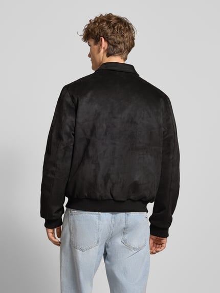 Männermodel trägt Jacke in Leder-Optik mit Label-Stitching von KARL KANI, Regular-Fit, Schwarz, Umlegekragen, Reißverschluss, Ganzkörperansicht Rückansicht