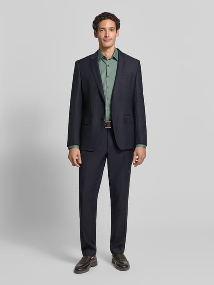 Männermodel trägt Slim Fit Businesshemd mit Kentkragen von OLYMP in grün, unifarben, strukturierte Webware, Ganzkörperansicht von vorne.
